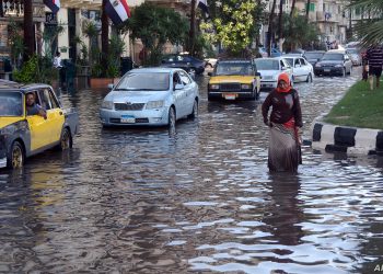 An Egyptian woman walks in a flooded street in Egypt's northern coastal city of Alexandria, following heavy rains, on October 25, 2015.  AFP PHOTO / STR (Photo by STR / AFP)