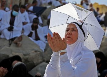 A Muslim woman prays atop Mount Arafat, also known as Jabal al-Rahma (Mount of Mercy), southeast of the Saudi holy city of Mecca, during the climax of the Hajj pilgrimage, on July 8, 2022. (Photo by Christina ASSI / AFP)