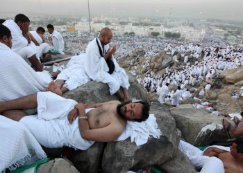 A Muslim pilgrim rests as others pray on Mount Mercy on the plains of Arafat, outside the holy city of Mecca, November 15, 2010. At least 2.5 million Muslims began the annual haj pilgrimage on Sunday, heading to an encampment near the holy city of Mecca to retrace the route taken by Prophet Mohammad 14 centuries ago. REUTERS/Mohammed Salem (SAUDI ARABIA - Tags: RELIGION SOCIETY)