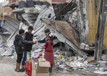 Palestinian children sell sweets in front of the rubble of a destroyed building in Jebaliya refugee camp, Gaza Strip, Tuesday, Nov. 28, 2023, on the fifth day of the temporary ceasefire between Hamas and Israel. (AP Photo/Mohammed Hajjar)