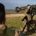 A British armed forces instructor holds a Javelin anti-tank system as he speaks with Ukrainian recruits during a five-week combat training course with the UK armed forces near Durrington in southern England on October 11, 2022. Ukrainian soldiers charge across a plain, brandishing rifles as smoke drifts from an explosion. But the recent recruits are not on the front line back home. They are in Britain, where the army is helping them to learn vital battlefield skills. (Photo by Daniel LEAL / AFP)